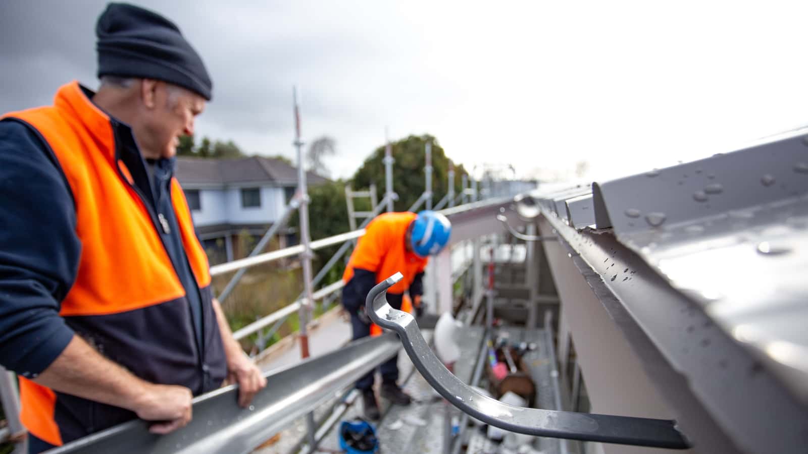 Installer fitting half-round gutters to the corner of a house